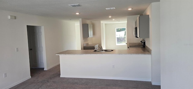 kitchen with stove, sink, kitchen peninsula, and dark colored carpet