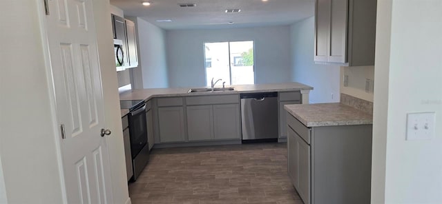 kitchen featuring appliances with stainless steel finishes, sink, kitchen peninsula, gray cabinets, and dark hardwood / wood-style floors