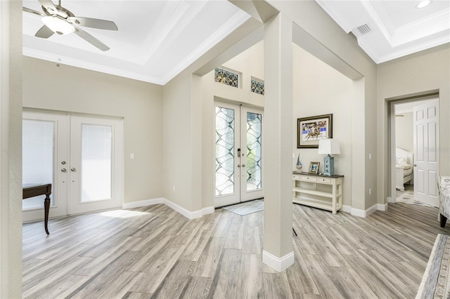 entrance foyer with ornamental molding, a tray ceiling, and french doors