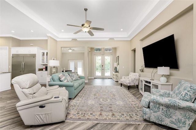 living room featuring hardwood / wood-style flooring, ceiling fan, a tray ceiling, crown molding, and french doors