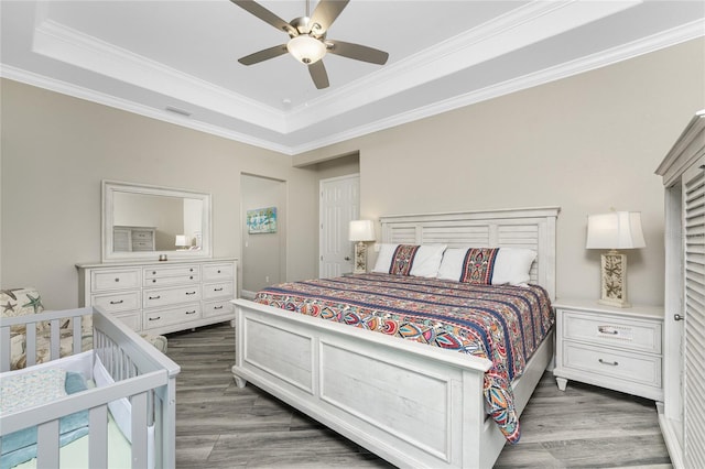 bedroom with ornamental molding, dark hardwood / wood-style floors, and a tray ceiling