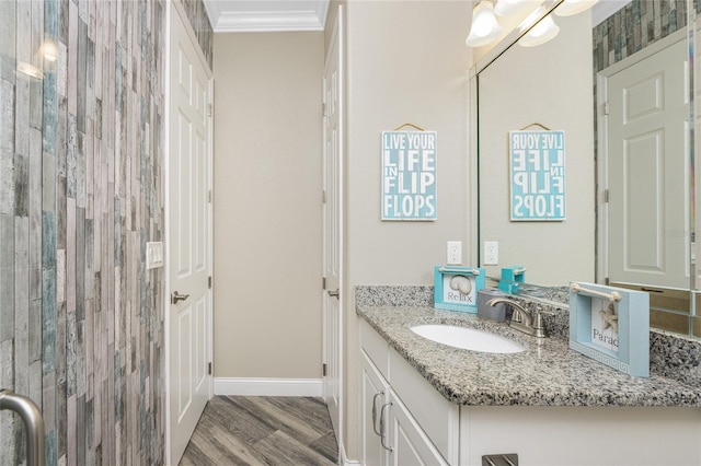 bathroom featuring hardwood / wood-style flooring, ornamental molding, vanity, and walk in shower