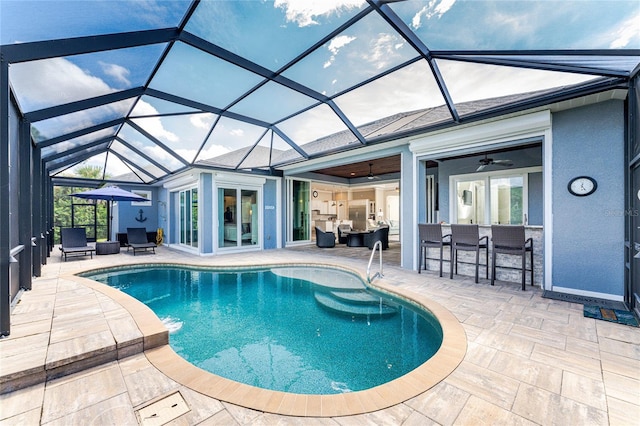 view of pool with a bar, a patio area, ceiling fan, and glass enclosure