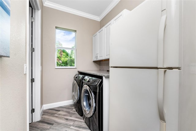 laundry room with cabinets, ornamental molding, washing machine and clothes dryer, and light hardwood / wood-style floors