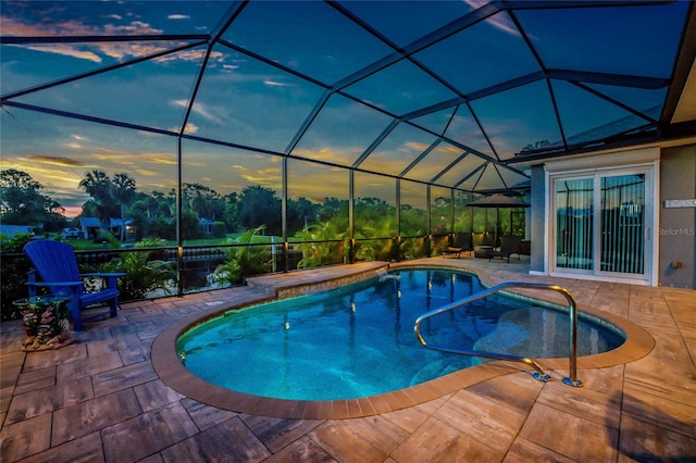 pool at dusk with a lanai and a patio area