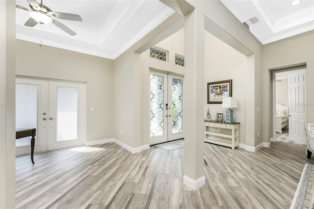 foyer with a raised ceiling, crown molding, and french doors