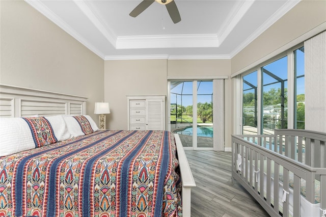 bedroom featuring ornamental molding, access to exterior, ceiling fan, light hardwood / wood-style floors, and a raised ceiling