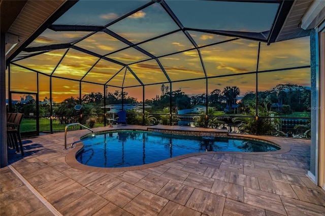 pool at dusk with a patio area and glass enclosure