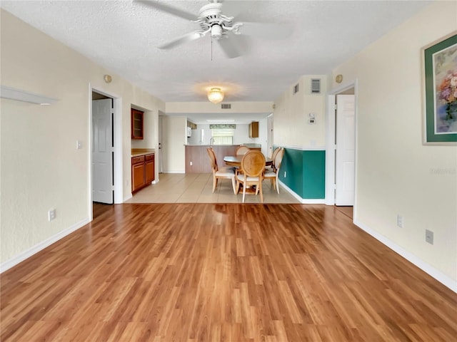 unfurnished living room with a textured ceiling, light tile patterned floors, and ceiling fan