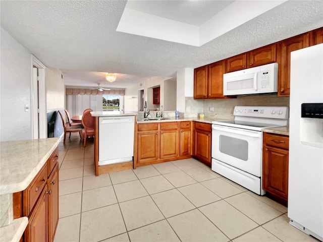 kitchen with light tile patterned flooring, white appliances, a textured ceiling, kitchen peninsula, and backsplash