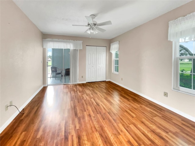 spare room featuring wood-type flooring, a wealth of natural light, and ceiling fan