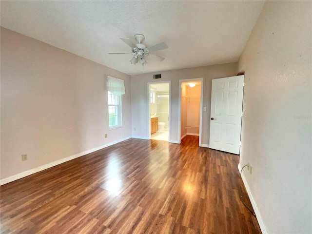 unfurnished bedroom with ceiling fan, a spacious closet, dark hardwood / wood-style floors, ensuite bathroom, and a closet