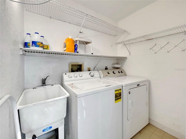 washroom featuring light tile patterned floors, washer and clothes dryer, and sink