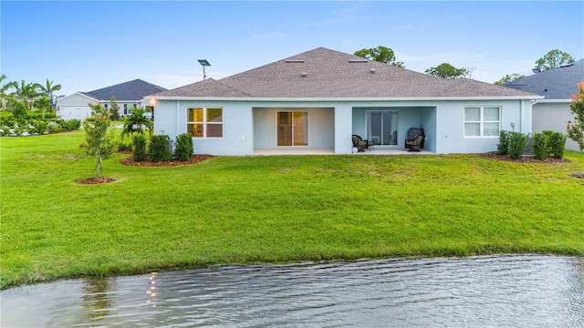 back of house with a patio, a yard, a water view, and stucco siding