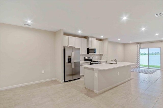 kitchen with visible vents, an island with sink, appliances with stainless steel finishes, a sink, and backsplash