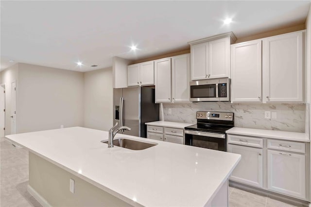 kitchen featuring light tile patterned flooring, stainless steel appliances, a sink, tasteful backsplash, and a center island with sink