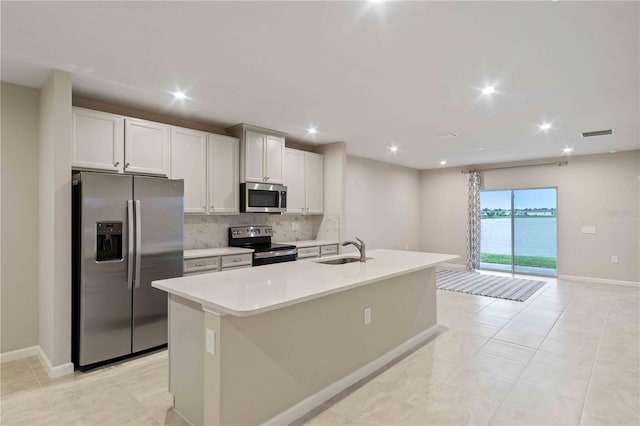 kitchen featuring tasteful backsplash, visible vents, an island with sink, appliances with stainless steel finishes, and a sink