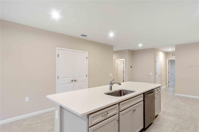 kitchen featuring baseboards, dishwasher, an island with sink, light countertops, and a sink