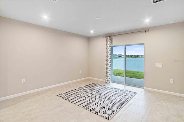 empty room with tile patterned floors, recessed lighting, a water view, and baseboards