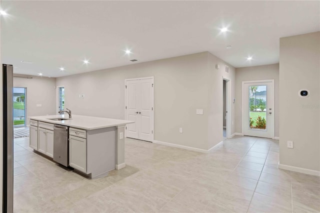 kitchen featuring dishwasher, a kitchen island with sink, light countertops, a sink, and recessed lighting