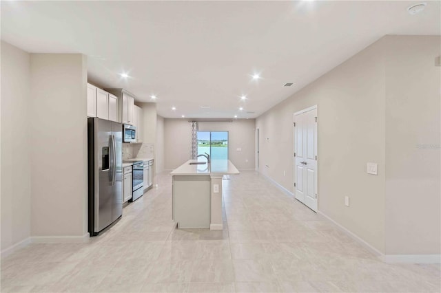 kitchen with stainless steel appliances, light countertops, a kitchen island with sink, a sink, and white cabinetry