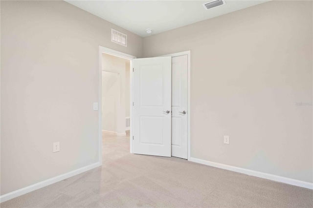 unfurnished bedroom with light carpet, visible vents, and baseboards