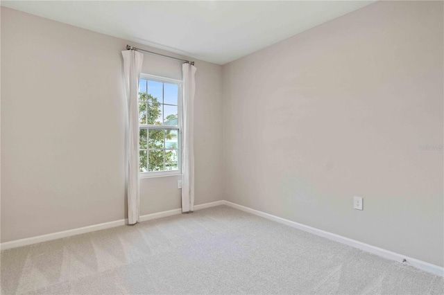 empty room featuring light carpet and baseboards