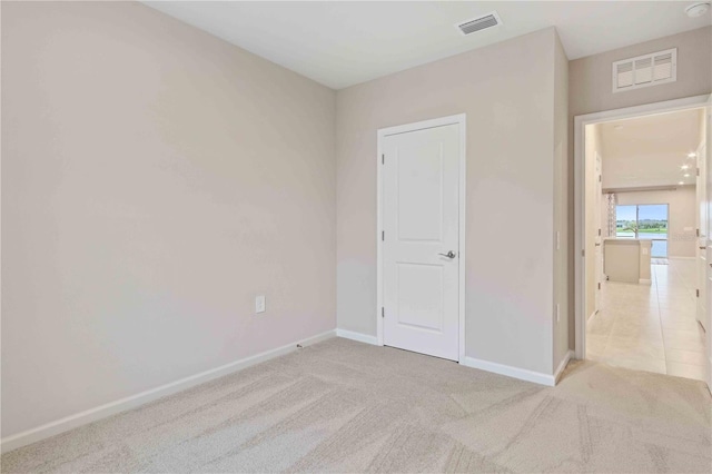 unfurnished bedroom featuring light colored carpet, visible vents, and baseboards