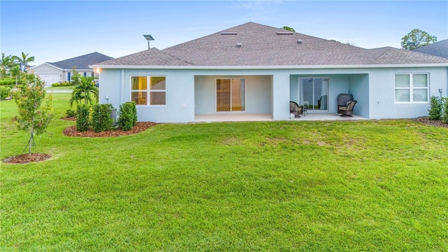 back of house featuring a yard, a shingled roof, stucco siding, and a patio