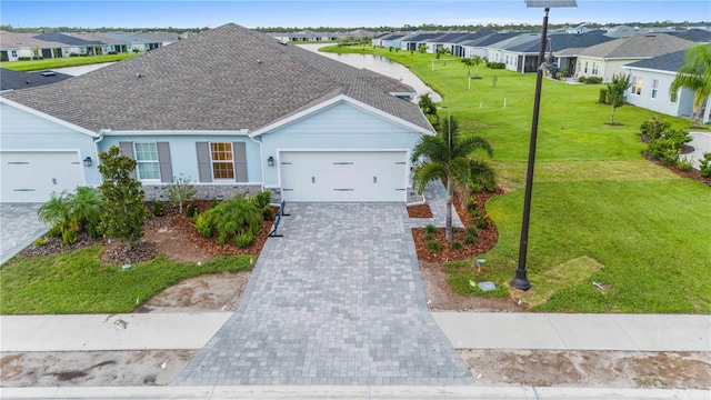 view of front of property with decorative driveway, a shingled roof, an attached garage, a residential view, and a front lawn