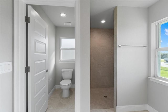 bathroom featuring toilet, tile patterned floors, and tiled shower