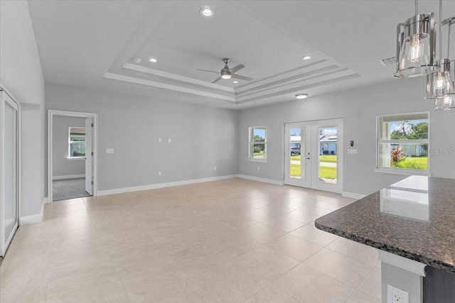 unfurnished living room featuring ceiling fan, french doors, and a tray ceiling