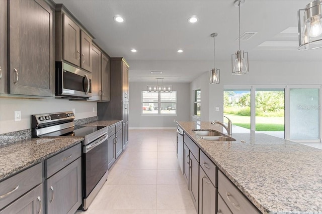 kitchen with stainless steel appliances, light stone countertops, a wealth of natural light, pendant lighting, and sink