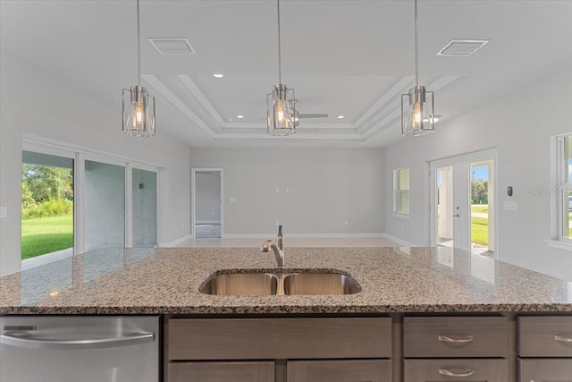 kitchen featuring dishwasher, a tray ceiling, and light stone counters