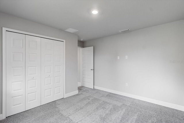 unfurnished bedroom with light colored carpet and a closet