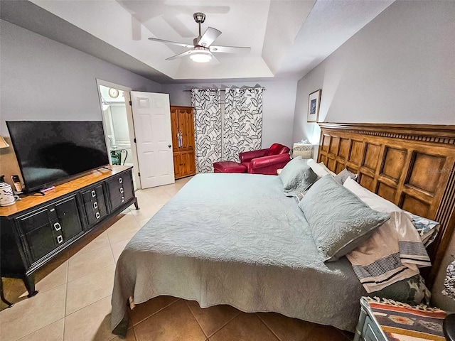 bedroom with ceiling fan, light tile patterned floors, and a tray ceiling