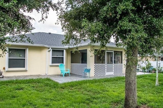 back of house featuring a lawn, a sunroom, and a patio area