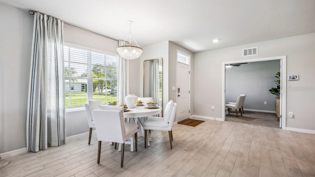 dining space with light wood-type flooring and an inviting chandelier