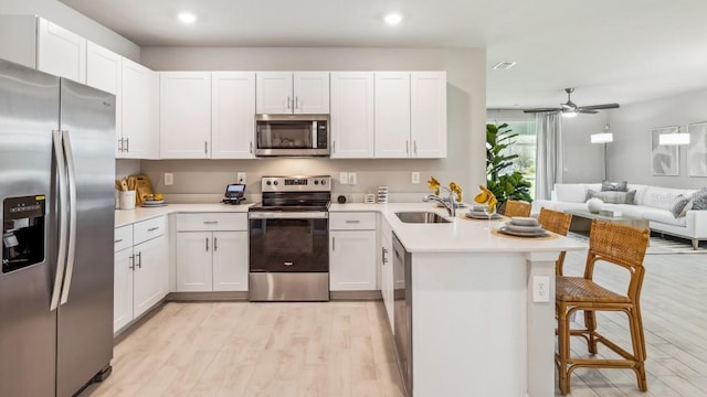 kitchen with a kitchen bar, kitchen peninsula, appliances with stainless steel finishes, and white cabinetry