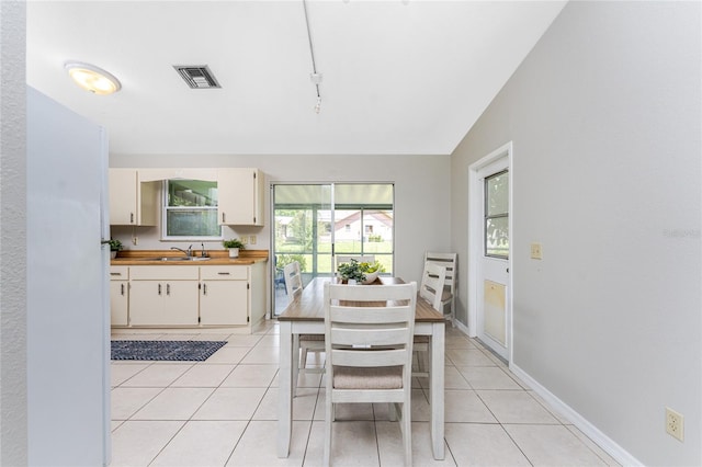 dining area featuring rail lighting, sink, vaulted ceiling, and light tile patterned flooring