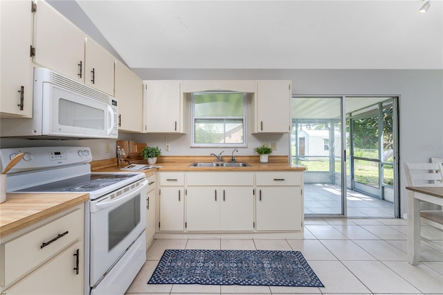 kitchen with light tile patterned floors, white cabinets, sink, and white appliances