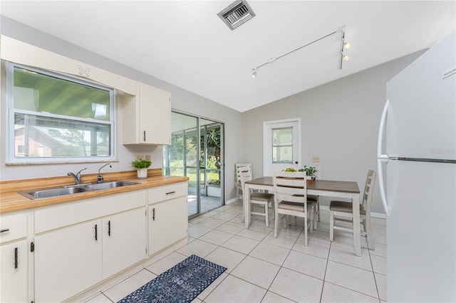 kitchen with white cabinets, sink, lofted ceiling, and white fridge