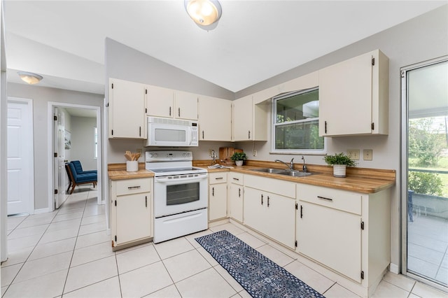 kitchen with lofted ceiling, light tile patterned floors, white appliances, and white cabinetry