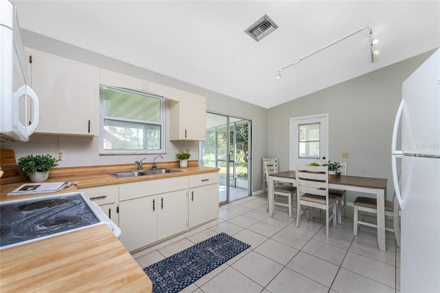 kitchen with sink, white cabinets, lofted ceiling, white appliances, and light tile patterned floors