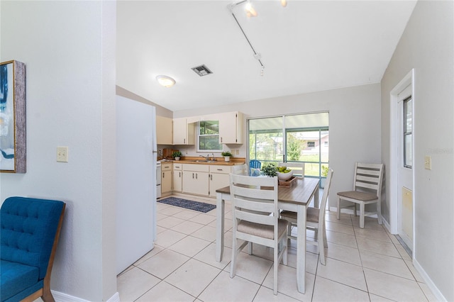 dining room with sink, light tile patterned floors, and rail lighting