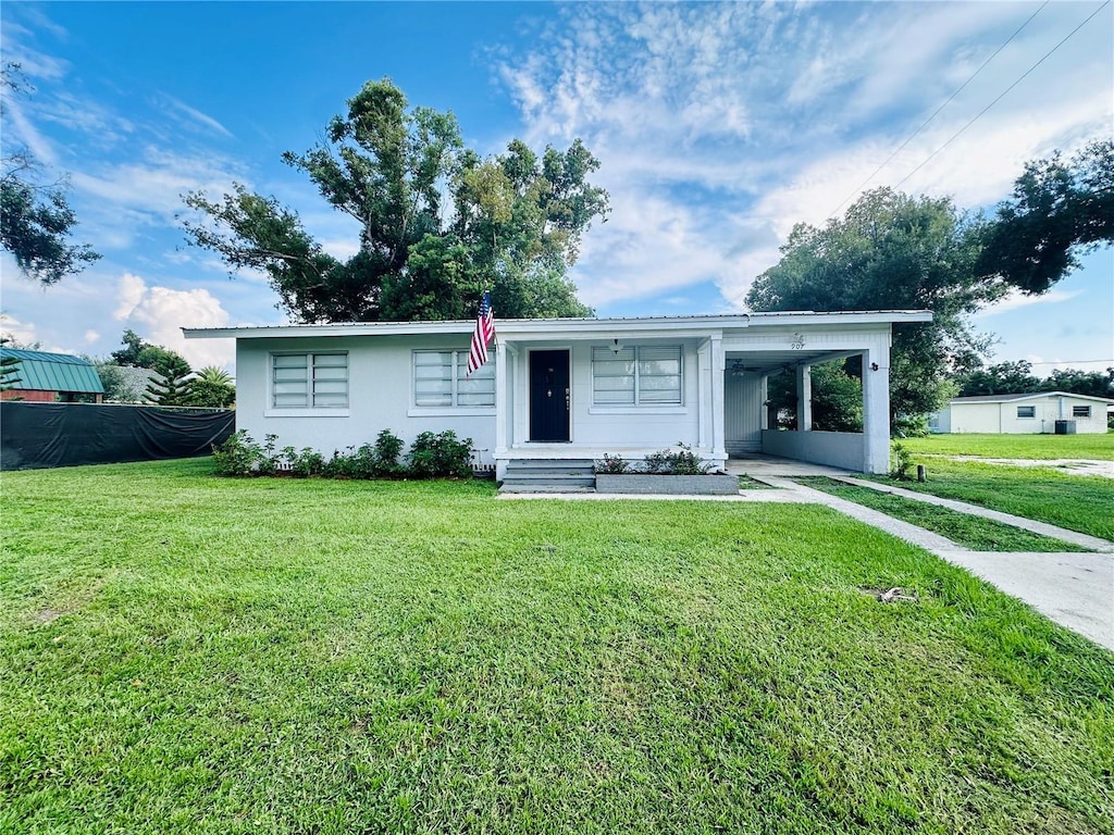 view of front of house with driveway, an attached carport, a front yard, and stucco siding