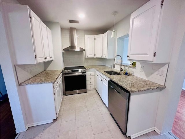 kitchen with white cabinets, wall chimney exhaust hood, light stone counters, stainless steel appliances, and a sink