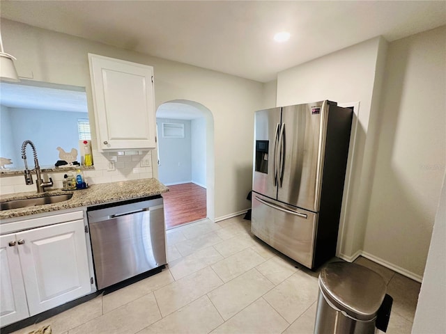 kitchen with backsplash, white cabinetry, stainless steel appliances, and a sink