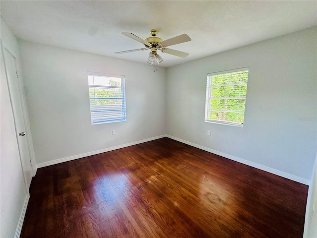unfurnished room featuring a ceiling fan, dark wood-style flooring, and baseboards