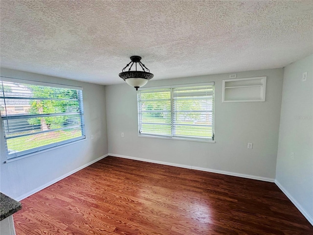unfurnished room featuring a textured ceiling, baseboards, and wood finished floors